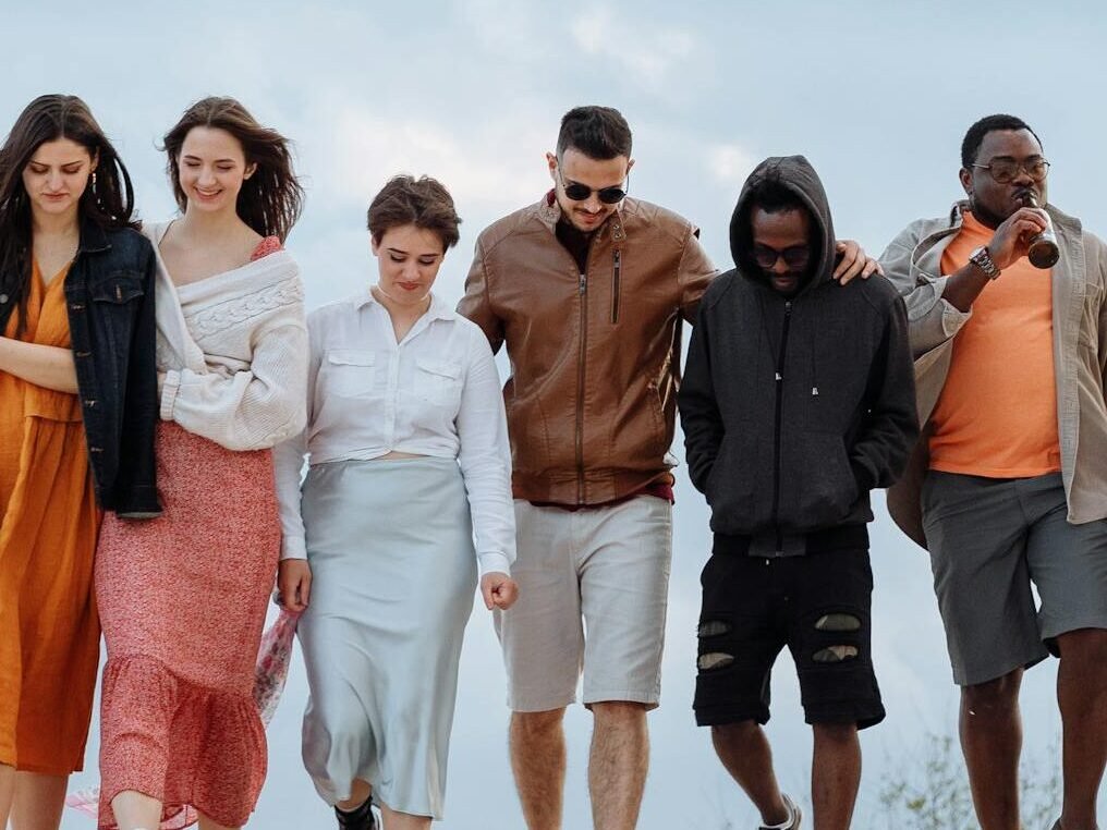 A diverse group of friends enjoying a walk under a cloudy sky, depicting unity and leisure.