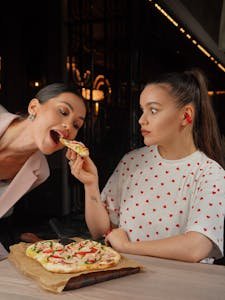 Two young women enjoying pizza together in a chic indoor restaurant setting.