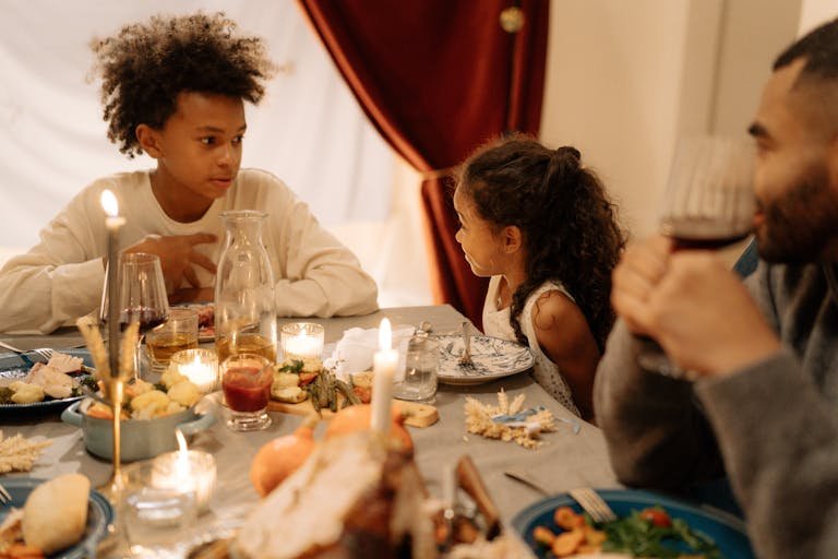 Warm family gathering around a candlelit dinner table, sharing a festive meal indoors.