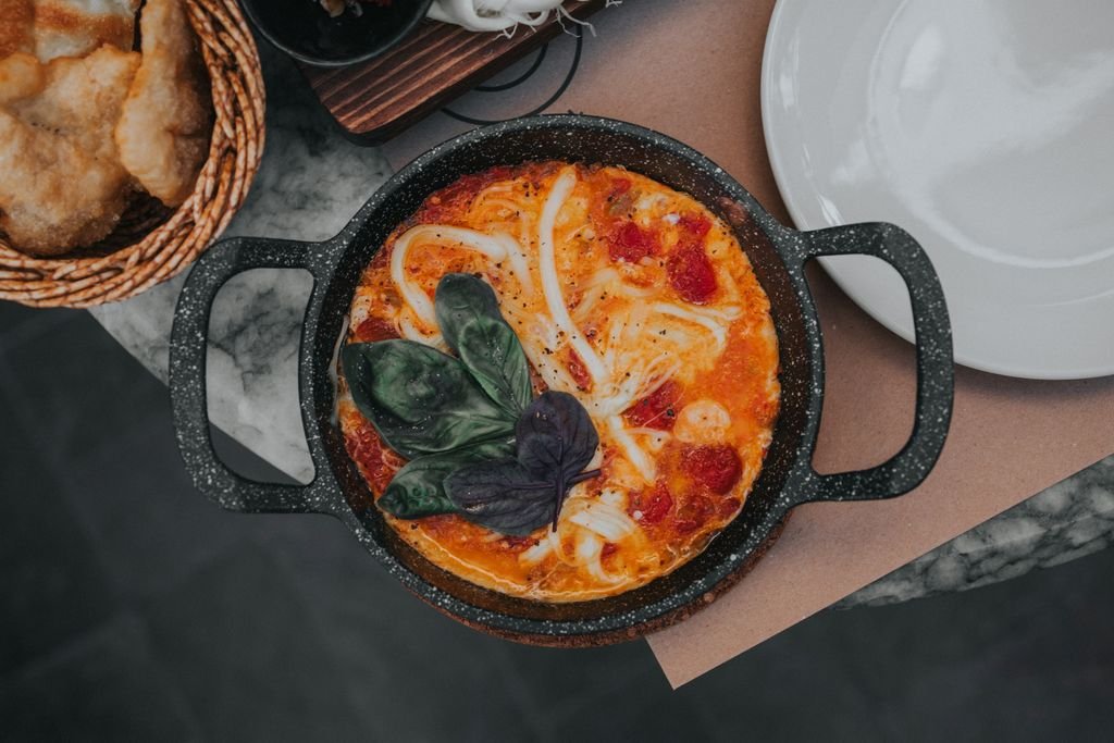 Top view of shakshuka with spinach in a black pan, perfect for breakfast or brunch.